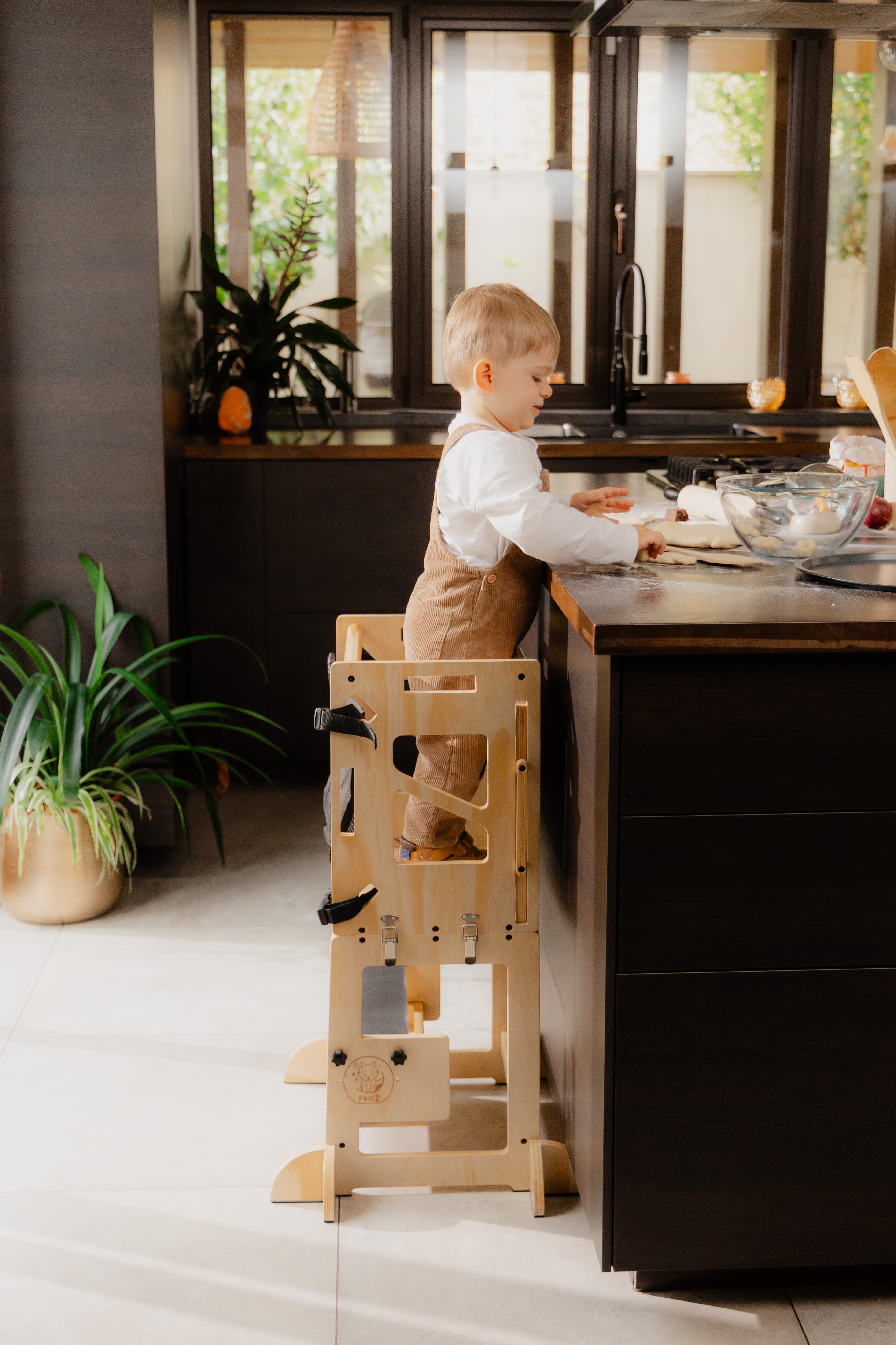 Enfant debout dans la tour d'apprentissage Montessori VersaTower, à hauteur du plan de travail